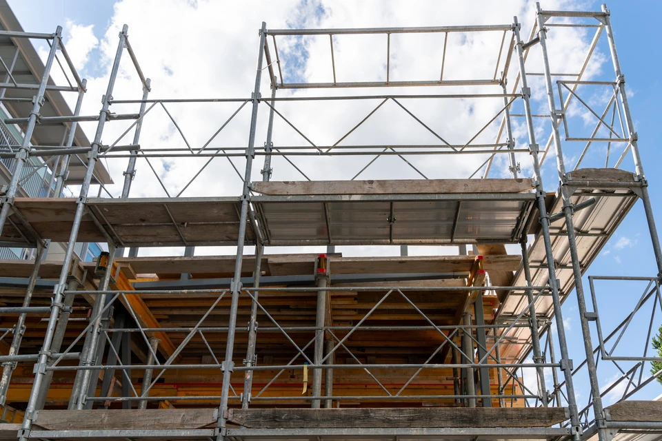Chantier de construction extérieur avec échafaudage métallique tubulaire entourant un bâtiment en cours de rénovation