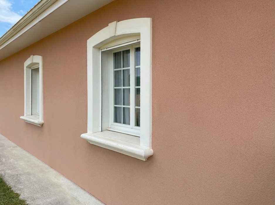 Façade extérieure d'une maison enduite, peinte en rose poudré